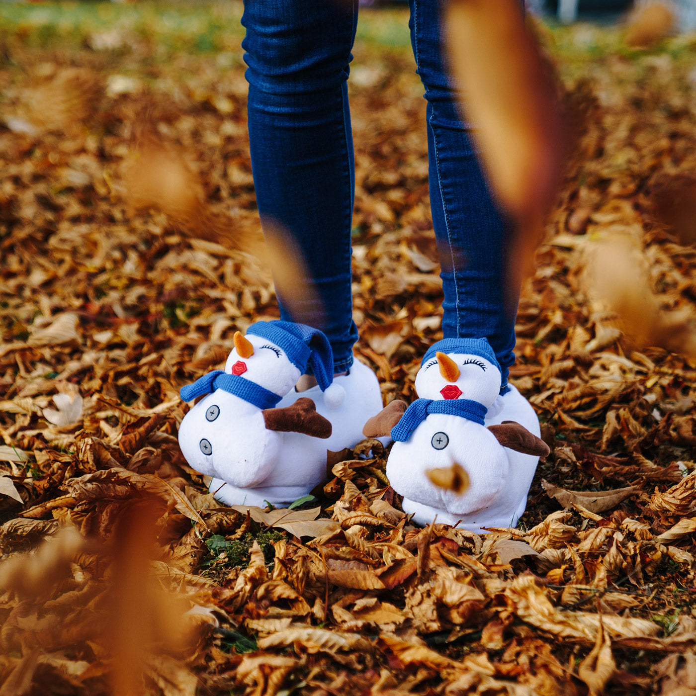 Person steht im Laub und trägt Schneemann Hausschuhe